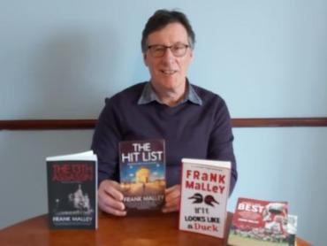 man sitting behind a display of books