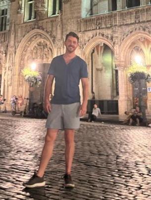 man standing on cobbled street in tshirt and shorts