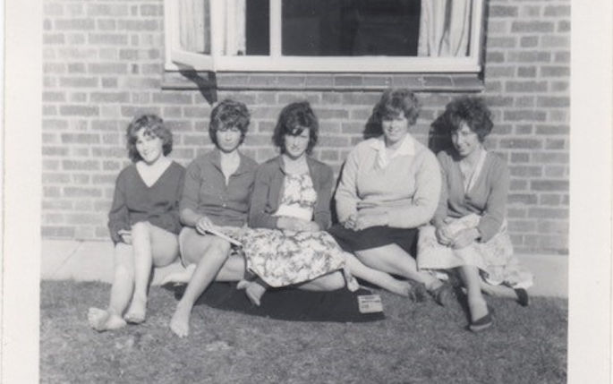 4 vet students from the 1960s sit outside a building in the summer