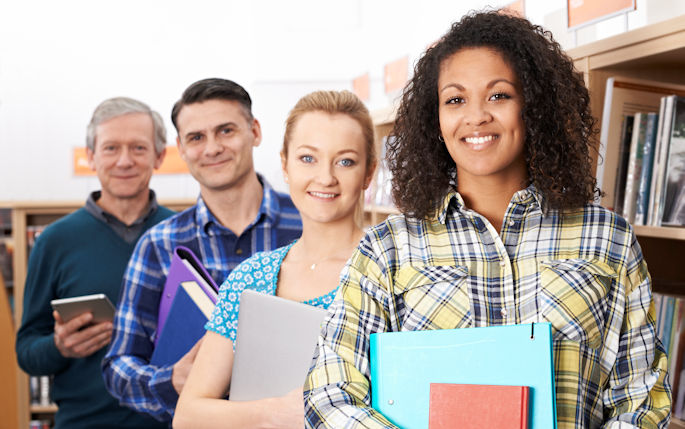 A picture of four people holding folders smiling at the camera