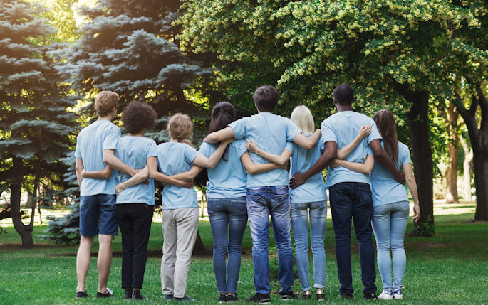 A line of people stand with their backs to the camera linking arms