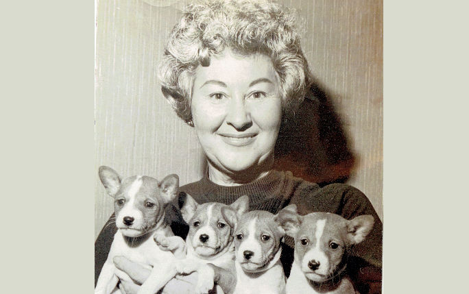 A black and white picture of Constance Graham with 4 small puppies held in front of her