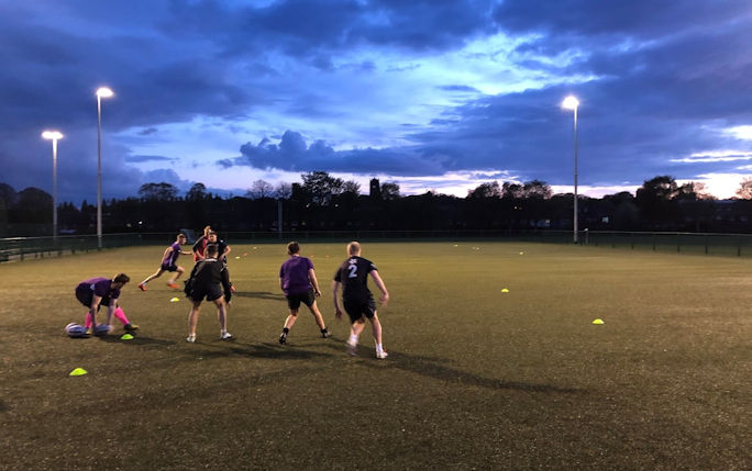 A picture of the vets rugby team as they play at dusk