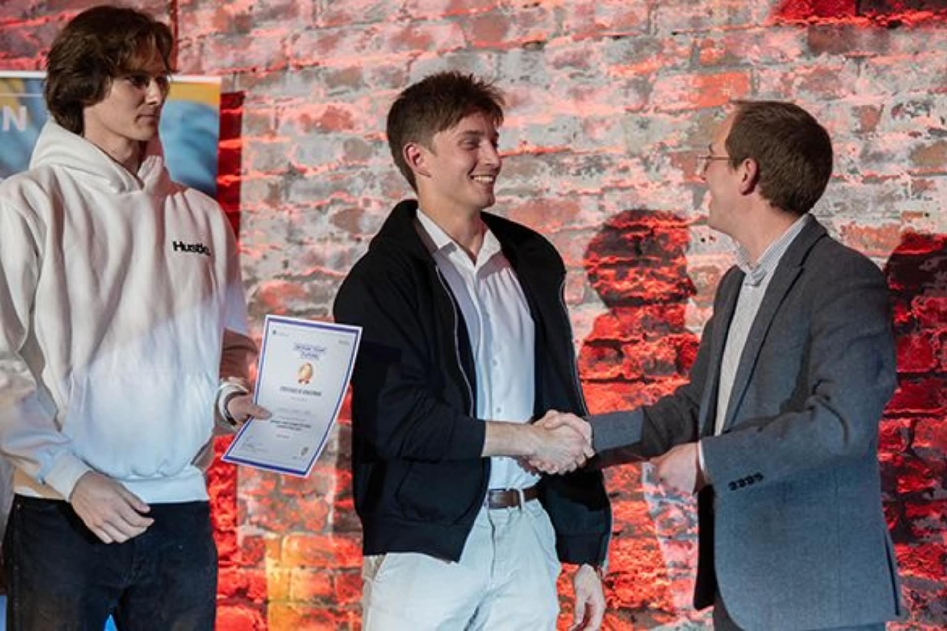 three people on stage winning competiton