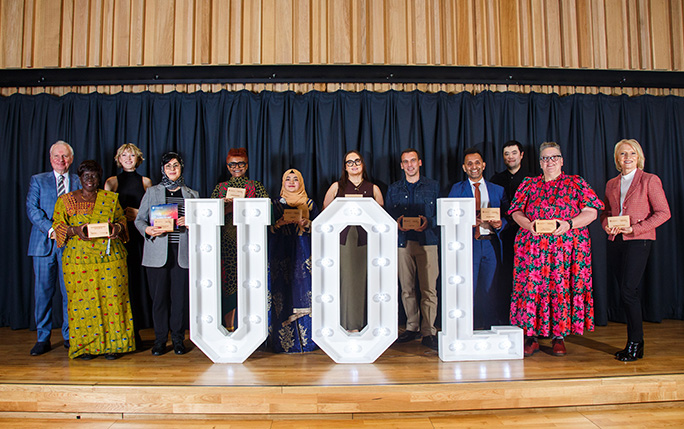 Graduates on stage with their awards behind UOL shaped letters