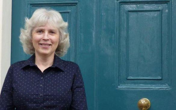 Anna smiling, standing in front of a blue door