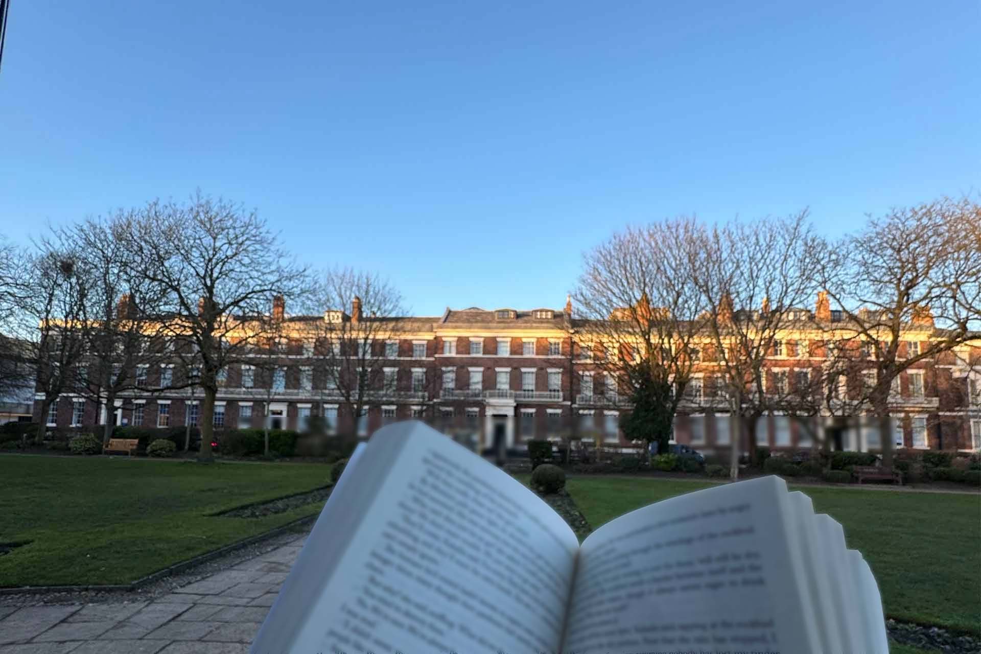 Book pictured on a square with building in the background