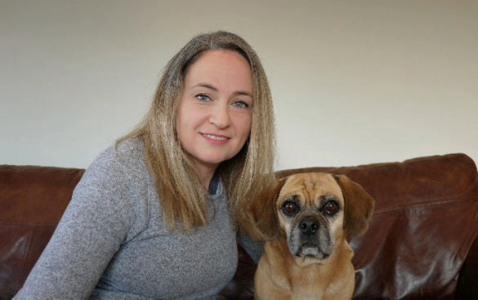 Carri and her dog sitting on the sofa posing for a photo