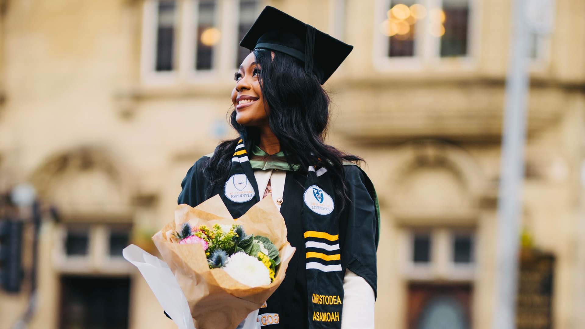 Graduate with flowers poses for photo