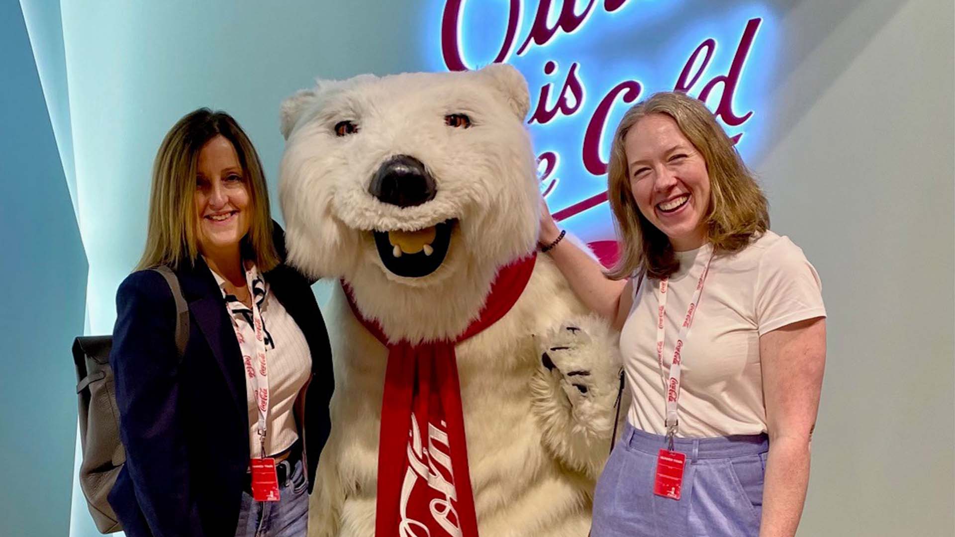 Two people on a tour pose for a photo with someone in a polar bear suit