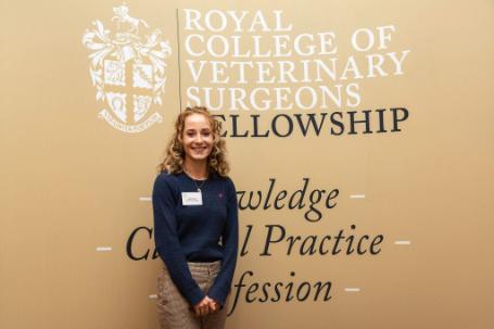 Daisy smiling, stood in front of the RCVS Fellowship board
