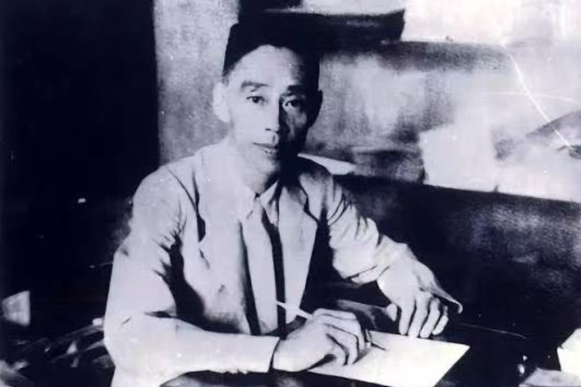 Image of Dr Fuqing Yan sitting at a desk with a pen and paper
