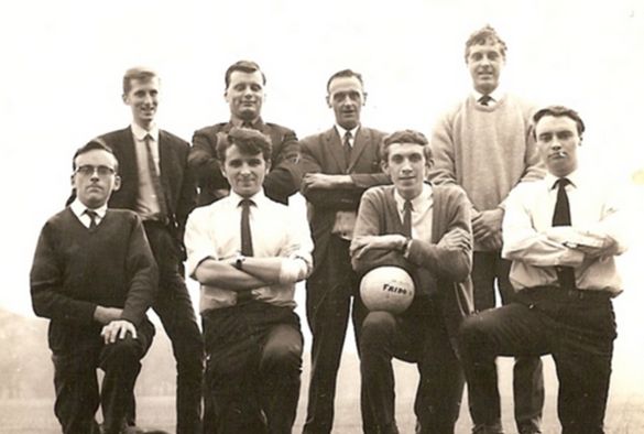 Black and white photo of a group of men in shirts and ties posing with their football