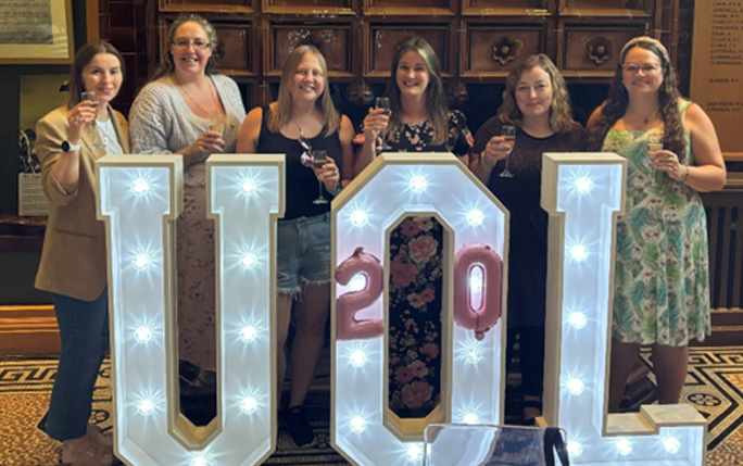 people pose in front UOL letters