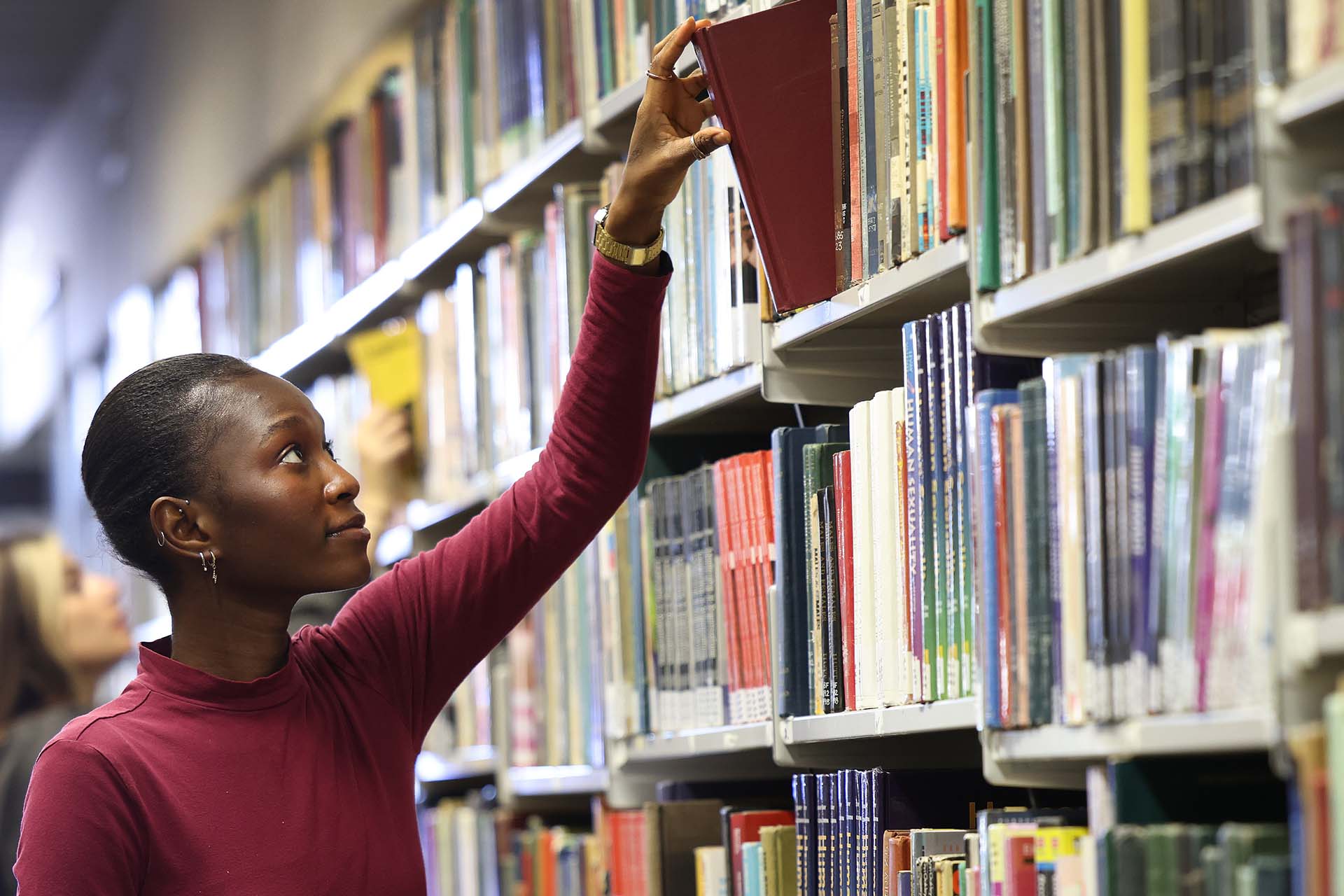 person pulling a book of a bookshelf