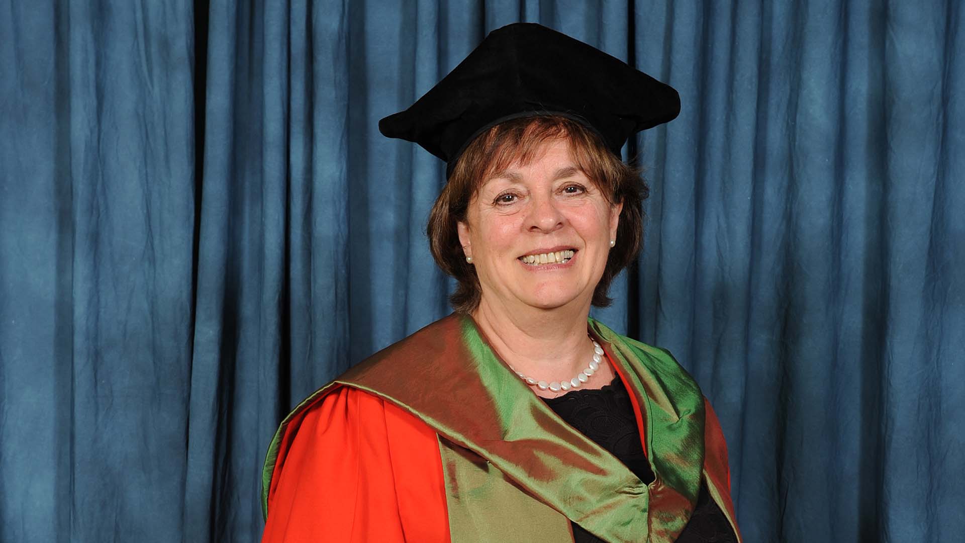 Woman in graduating cap and gown smiling at camera