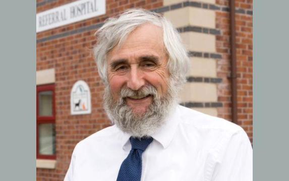 Geoff smiling in front of a red brick building