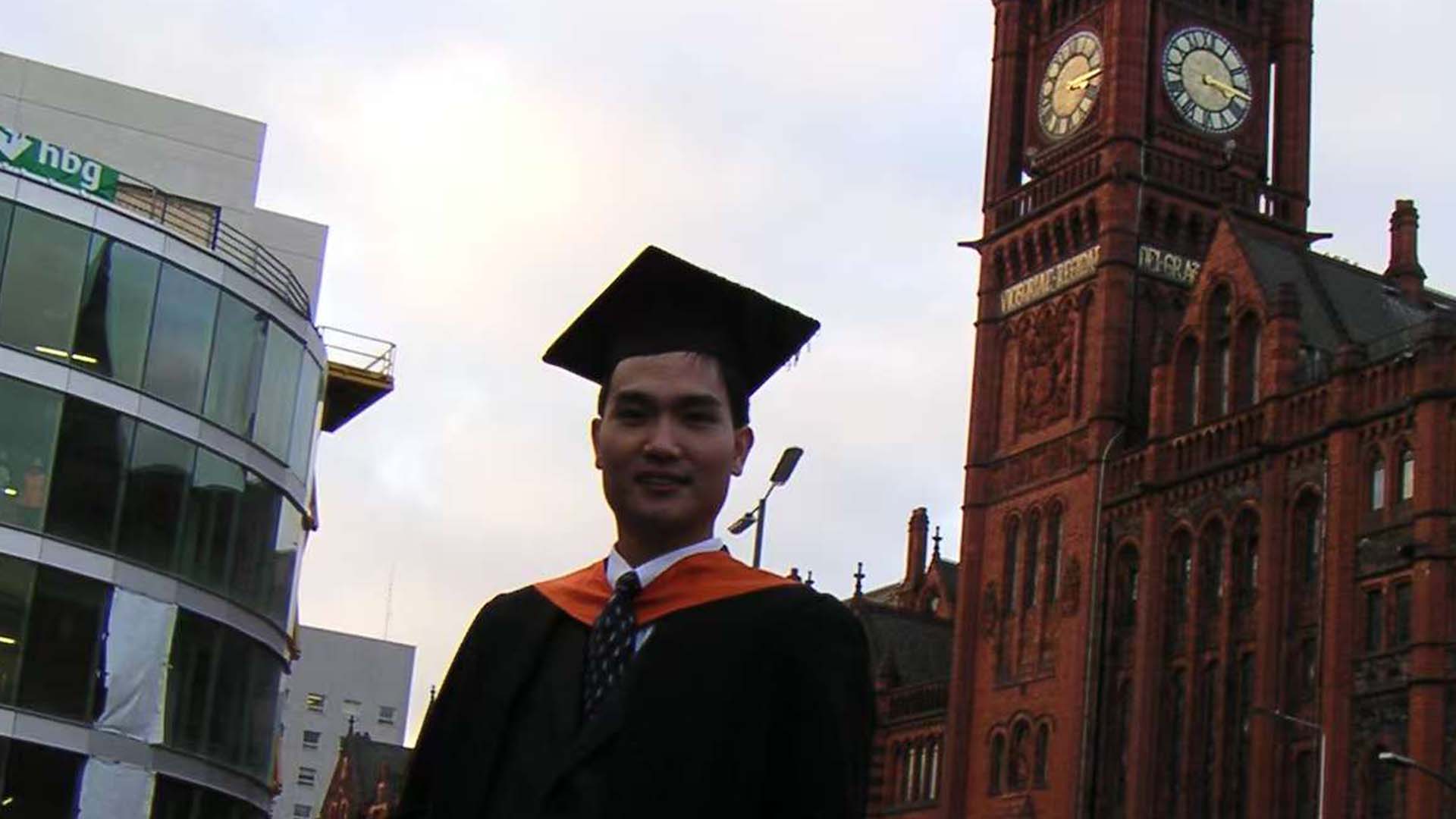 a graduate posing in front of a clock tower