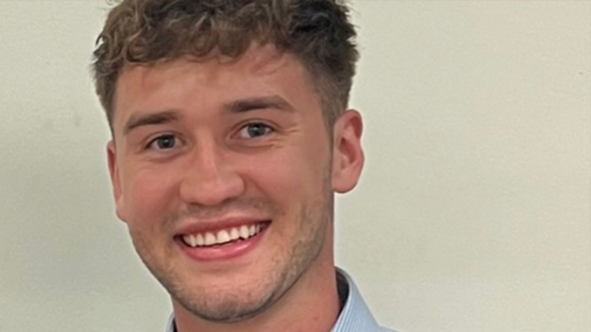 Person smiling at the camera wearing a blue shirt