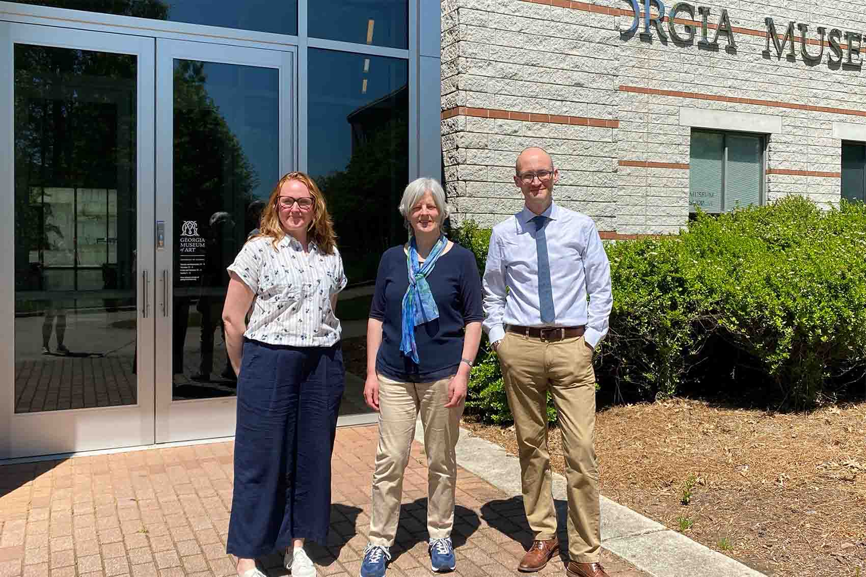 Three people stood in front of a building