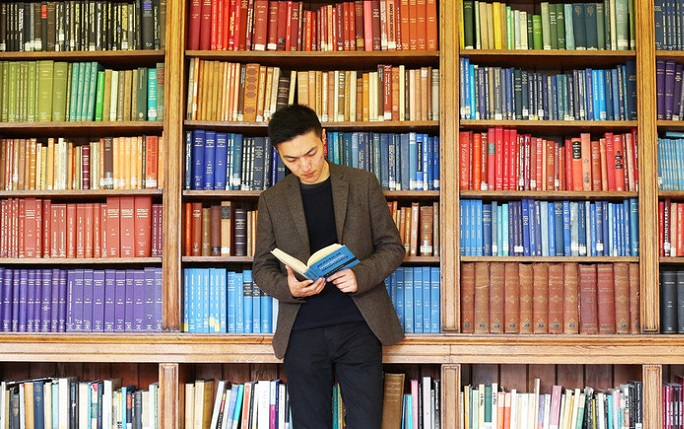 Student standing in front of bookcase