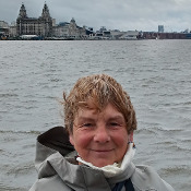 Lydia posing for a photo with the river Mersey and the Liverpool waterfront in the background