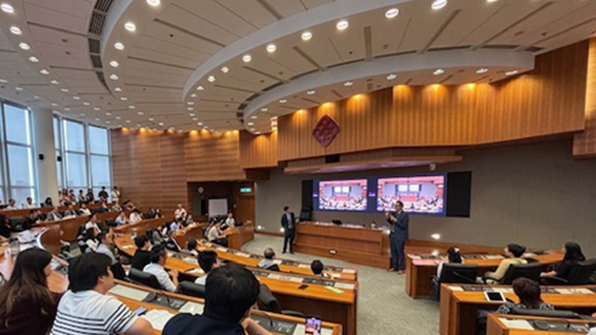 Lecture style room with people listening to a talk