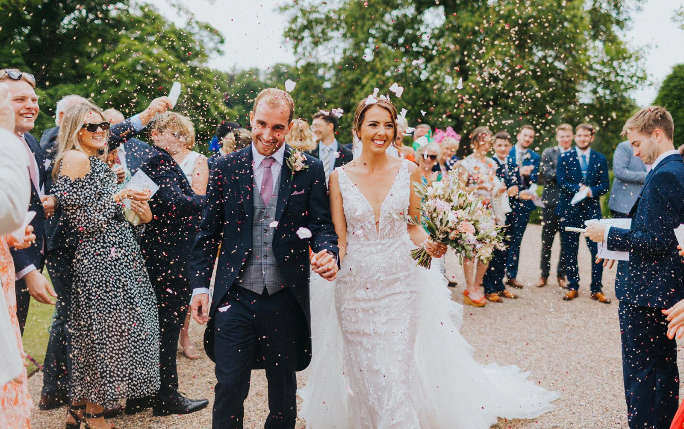 Rowan and his wife Harriet holding hands on the day of their wedding among family and friends