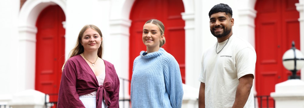 Three students standing in front of a red door