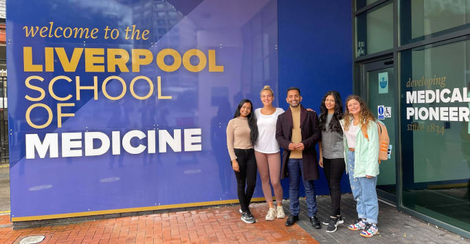 a group of people pose in front of a sign that reads Liverpool School of Medicine