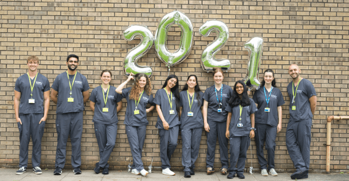 students in grey scrubs pose with balloons numbered 2 0 2 1